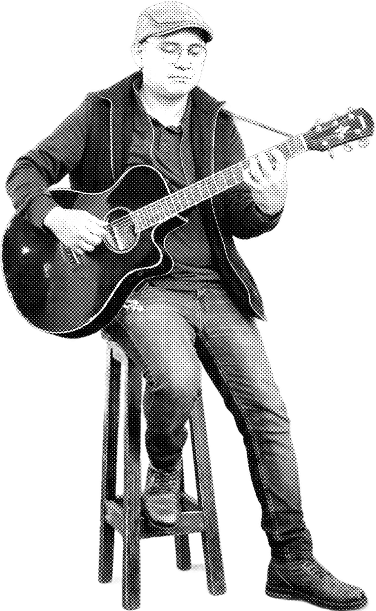 El músico del sábado, sentado en un banco tocando una guitarra acústica